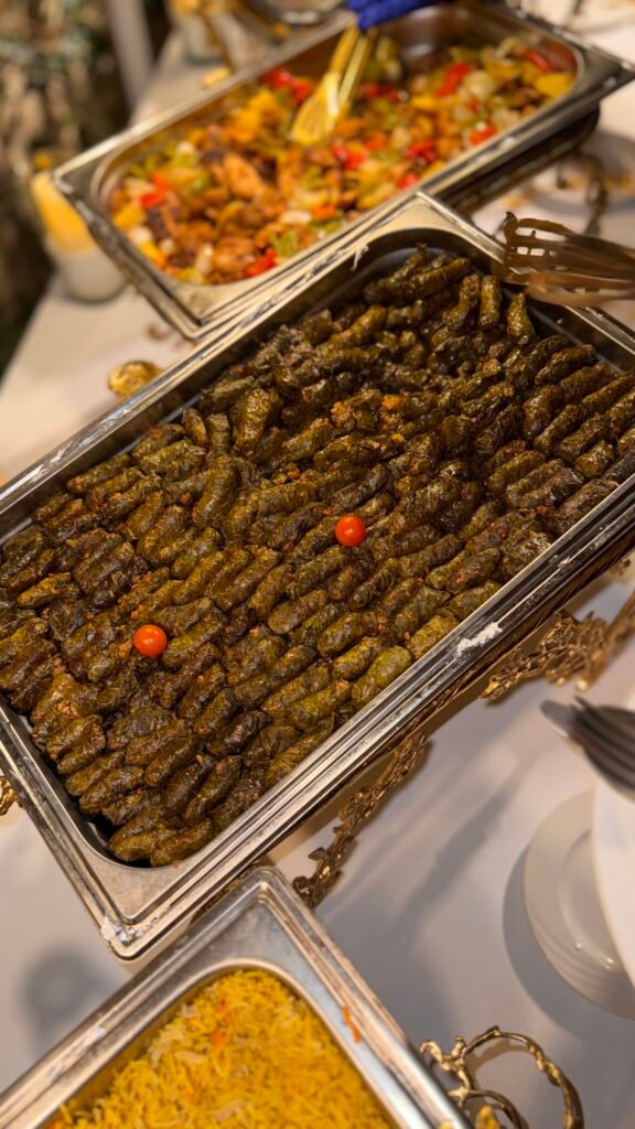 Luxury wedding catering buffet presentation in Cairo, 2026. The open-air display features premium seared beef, fresh seafood platters, and elaborate floral decor. Seamless service guaranteed by expert staff